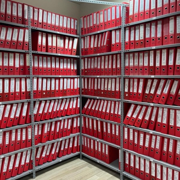 Çelik raf sisteminde düzenli şekilde yerleştirilmiş arşiv klasörleri